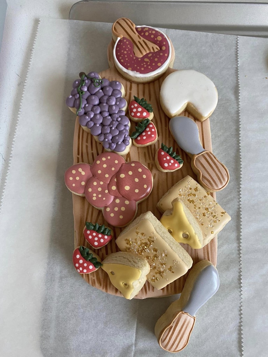 Cookie charcuterie board with decorated sugar cookies shaped like grapes, cheese, and fruit